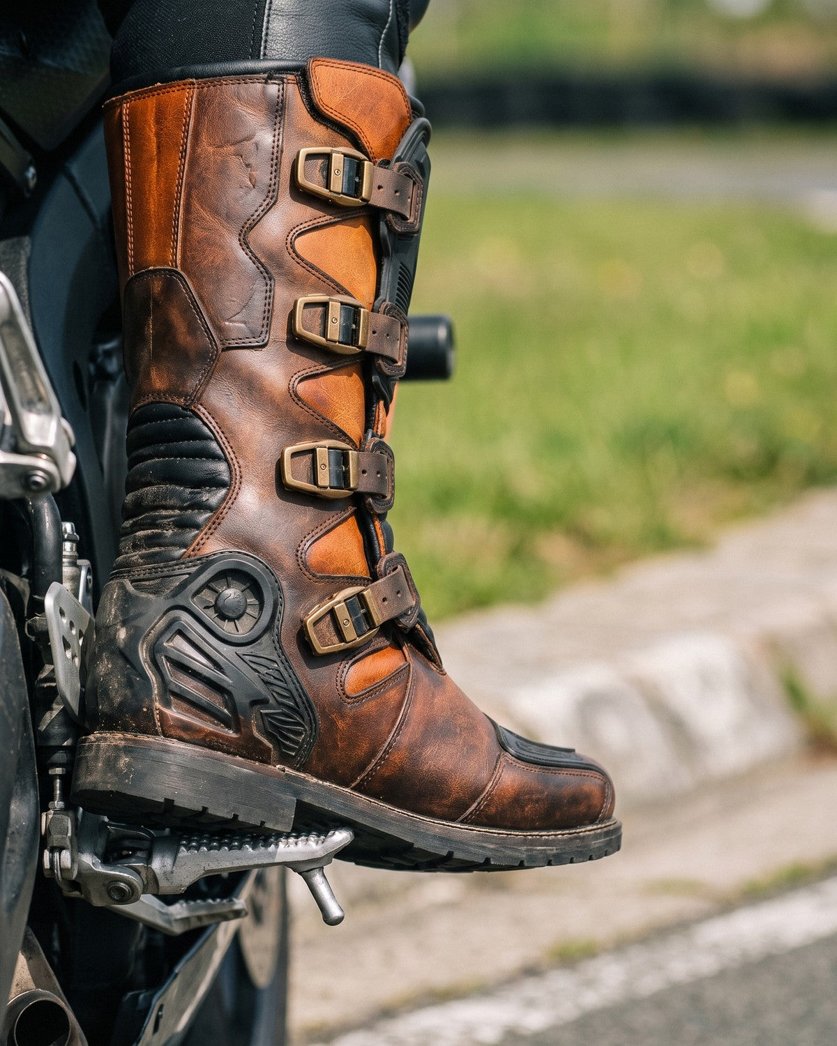 Copper and black heritage racing boot on a sportbike footpeg at trackside