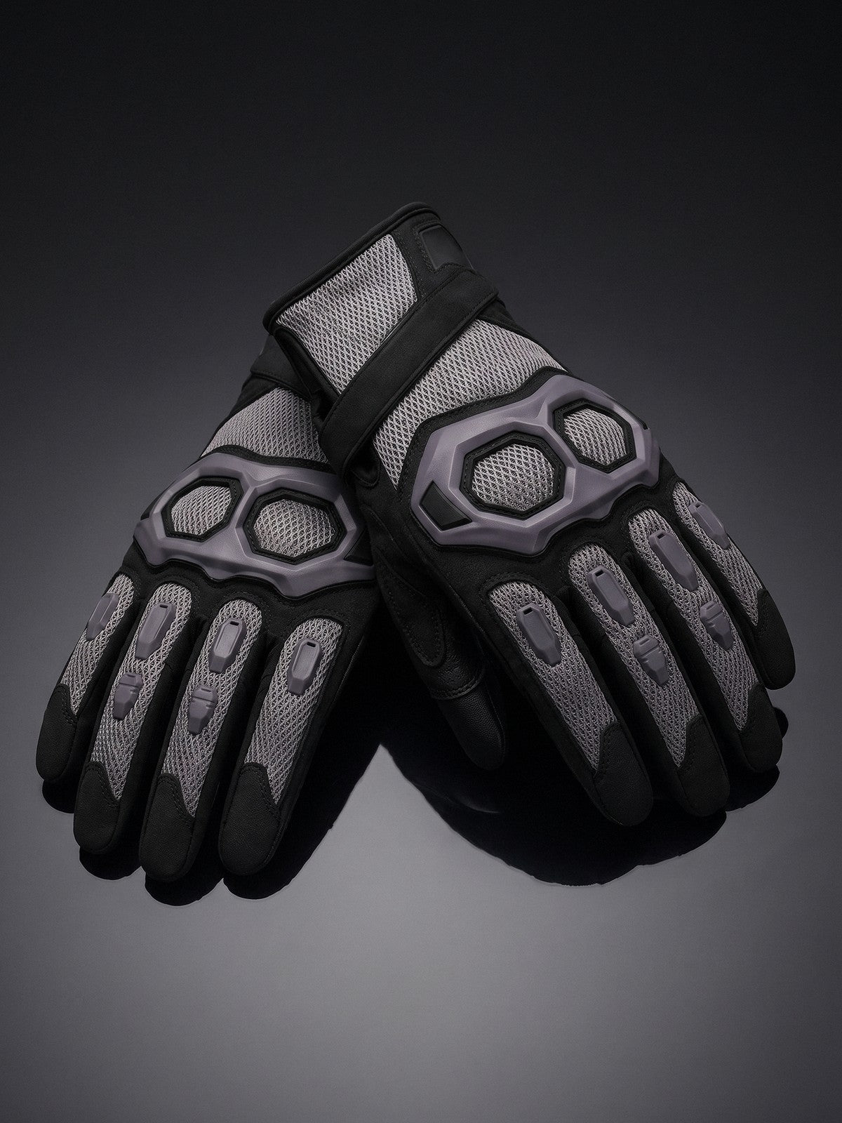 Pair of black structured-vent mesh motorcycle gloves on a dark studio backdrop