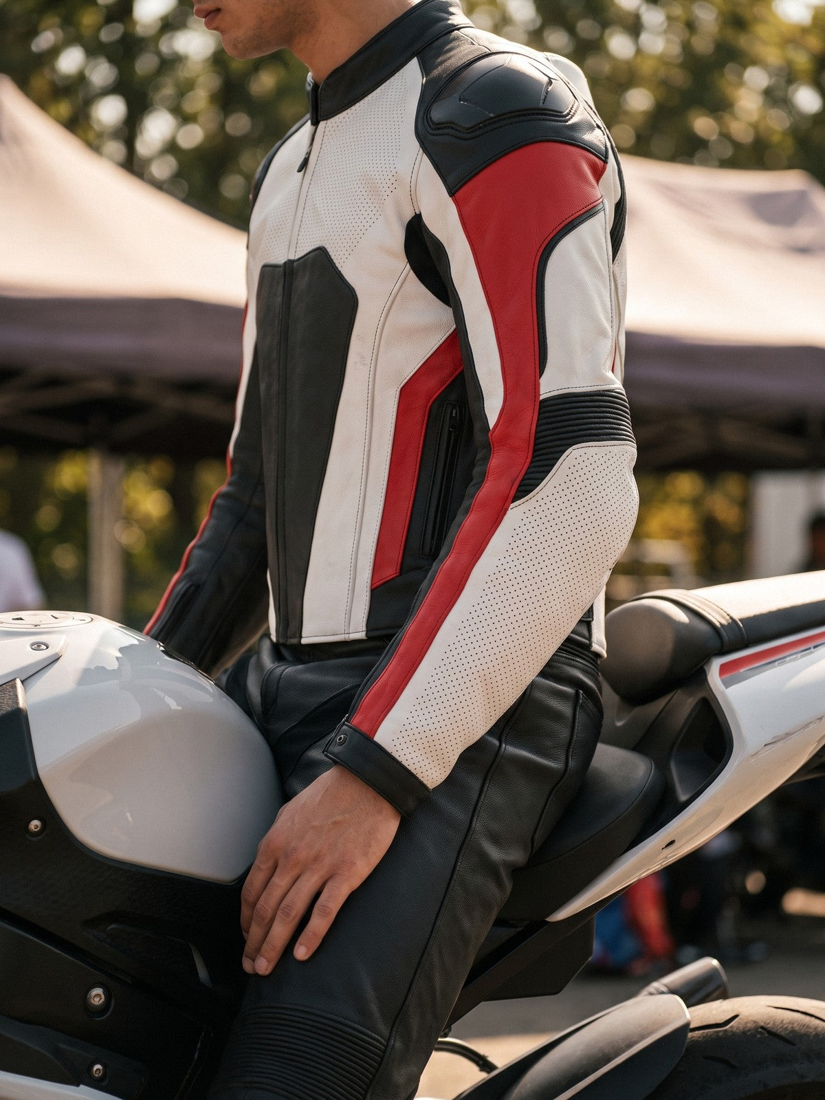 Racer in a white, red and black leather racing jacket beside a sportbike