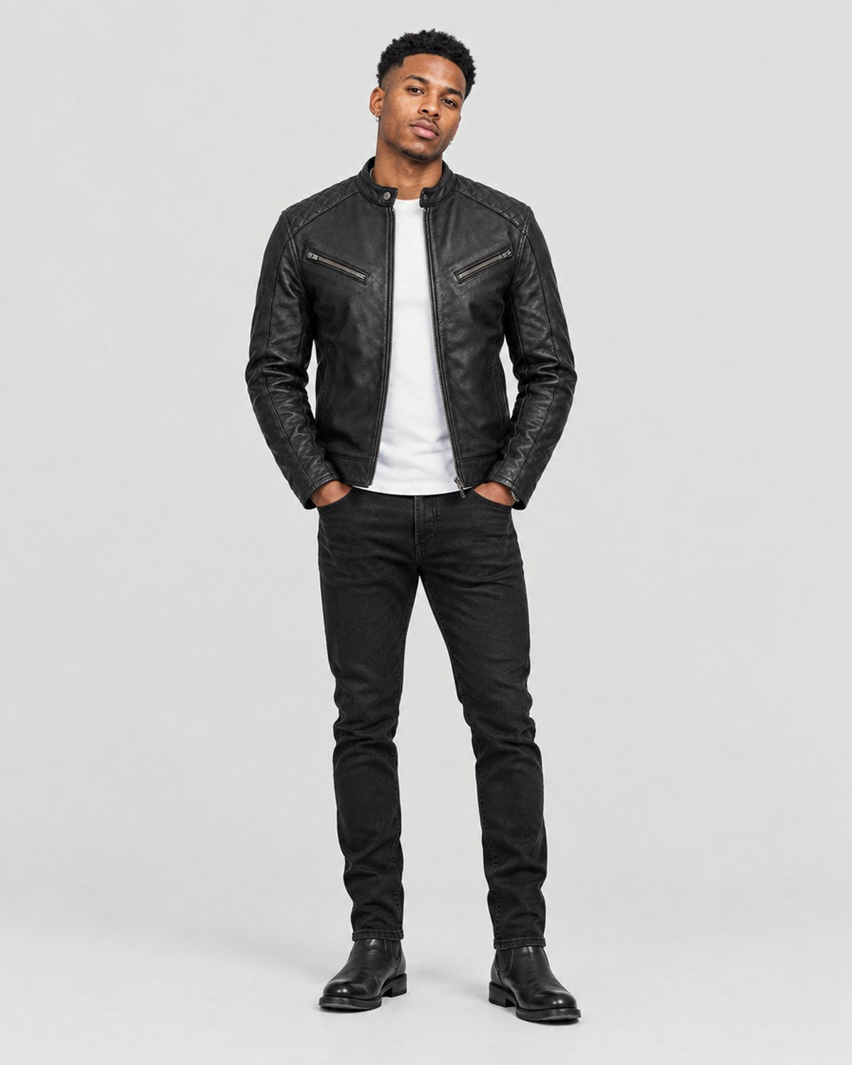 Model wearing a black leather motorcycle jacket in a grey studio