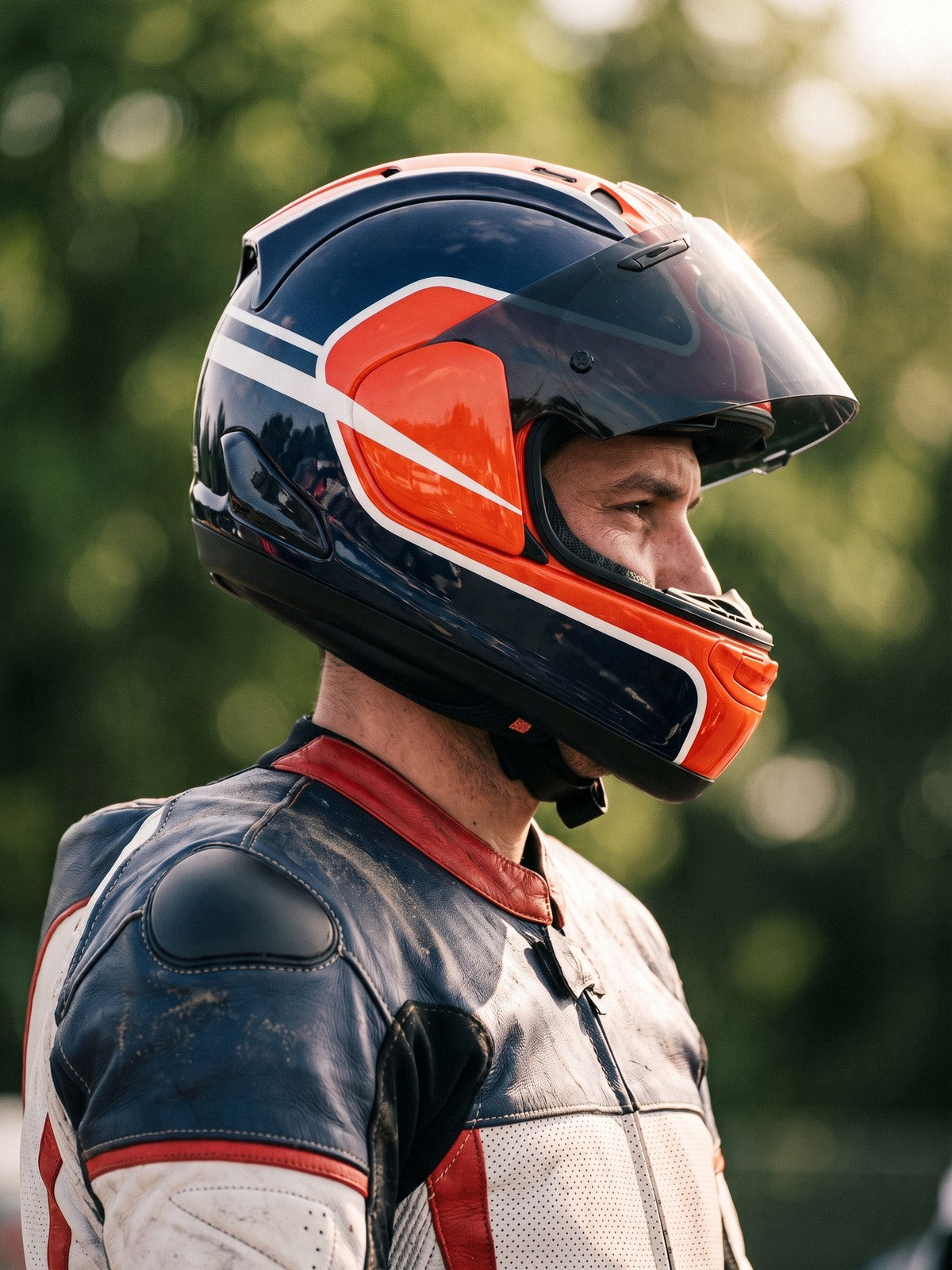 Road racer in profile wearing a navy and orange helmet and a navy, white and red one-piece leather suit